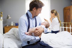 Родители при молодой младенец одевая для работы в спальне стоковые фото Родители при молодой младенец одевая для работы в спальне стоковые фото