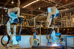 Роботы команды промышленные сваривают часть автомобиля собрания стоковая фотография rf Роботы команды промышленные сваривают часть автомобиля собрания стоковая фотография rf