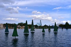Рождественская елка на озере, русских горках и красочных магазинах на облачном небе на теме Seaworld стоковая фотография Рождественская елка на озере, русских горках и красочных магазинах на облачном небе на теме Seaworld стоковая фотография