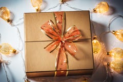 Рождество золотая подарочная коробка с красным смычком и красивая накаляя гирлянда против снега стоковое фото rf Рождество золотая подарочная коробка с красным смычком и красивая накаляя гирлянда против снега стоковое фото rf