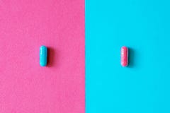 Розовые и голубые капсулы, пилюльки изолированные на bicolor розовом и голубой стоковое изображение rf Розовые и голубые капсулы, пилюльки изолированные на bicolor розовом и голубой стоковое изображение rf