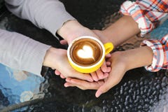 Романтичные пары в руке любов держа 2 чашки искусства latte с картиной сердце на таблице в кофейне стоковое фото Романтичные пары в руке любов держа 2 чашки искусства latte с картиной сердце на таблице в кофейне стоковое фото
