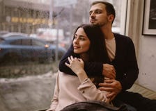 Романтичные пары Любя парень обнимает его красивую девушку сидя на windowsill в уютном кафе стоковое изображение Романтичные пары Любя парень обнимает его красивую девушку сидя на windowsill в уютном кафе стоковое изображение