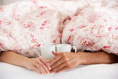 Романтичные руки удерживания пар под Duvet в кровати стоковое фото Романтичные руки удерживания пар под Duvet в кровати стоковое фото
