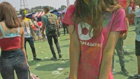 РОССИЯ, ИРКУТСК - 27-ОЕ ИЮНЯ 2018: Счастливое молодые люди танцуя и празднуя во время фестиваля Holi цветов Толпа РОССИЯ, ИРКУТСК - 27-ОЕ ИЮНЯ 2018: Счастливое молодые люди танцуя и празднуя во время фестиваля Holi цветов Толпа