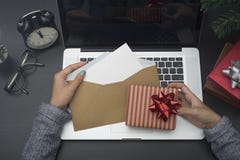 Рука бизнес-леди держа рождественскую открытку и подарочную коробку на столе стоковые изображения rf Рука бизнес-леди держа рождественскую открытку и подарочную коробку на столе стоковые изображения rf