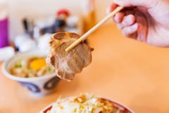 Рука держа Chashu палочками от рамэнов chashu Tonkotsu покрывая с капустой, ростком фасоли и чесноком стоковое изображение rf Рука держа Chashu палочками от рамэнов chashu Tonkotsu покрывая с капустой, ростком фасоли и чесноком стоковое изображение rf
