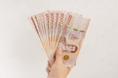 Рука держа новые 1000 банкнот тайского бата на белой предпосылке стены стоковая фотография rf Рука держа новые 1000 банкнот тайского бата на белой предпосылке стены стоковая фотография rf