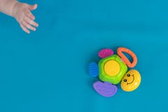 Рука ребенка достигает для пестротканой черепахи игрушки, которая завишущ против голубой предпосылки Диагональ : стоковые фотографии rf Рука ребенка достигает для пестротканой черепахи игрушки, которая завишущ против голубой предпосылки Диагональ : стоковые фотографии rf