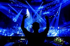 Руки DJ вверх на партии ночного клуба под голубым светом с толпой людей стоковые фотографии rf Руки DJ вверх на партии ночного клуба под голубым светом с толпой людей стоковые фотографии rf