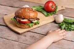Руки девушек около бургера гриба с сыром и томатами, сырцовыми champignons и салатом, прерывая доской стоковое изображение rf Руки девушек около бургера гриба с сыром и томатами, сырцовыми champignons и салатом, прерывая доской стоковое изображение rf