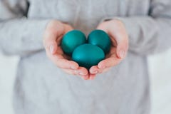 Руки держа современные пасхальные яйца покрашенный в зеленом цвете стоковое изображение rf Руки держа современные пасхальные яйца покрашенный в зеленом цвете стоковое изображение rf