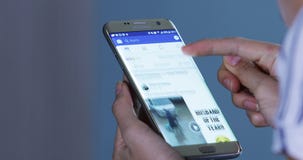 Руки женщины раскрывают Facebook app на smartphone Руки женщины раскрывают Facebook app на smartphone