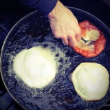 Руки кашевара жаря большое frybread в лотке масла стоковая фотография rf Руки кашевара жаря большое frybread в лотке масла стоковая фотография rf