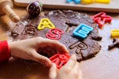 Руки мальчика детенышей отрезали печенья от сырцового теста на деревянном столе с красочными письмами Варить традиционные печенья стоковые изображения Руки мальчика детенышей отрезали печенья от сырцового теста на деревянном столе с красочными письмами Варить традиционные печенья стоковые изображения