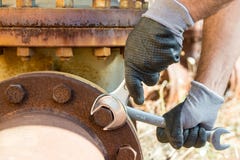 Руки при перчатки работы держа ключ и затягивают очень ржавые болты Стоковые Изображения Руки при перчатки работы держа ключ и затягивают очень ржавые болты Стоковые Изображения