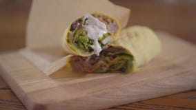 Руки шеф-повара в черных перчатках кухни делая конец-вверх shawarma Повар кладя наполовину shawarma с соусом на его видеоматериал Руки шеф-повара в черных перчатках кухни делая конец-вверх shawarma Повар кладя наполовину shawarma с соусом на его видеоматериал