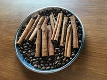 Ручки циннамона с кофейными зернами в шаре металла на деревянном столе стоковая фотография rf Ручки циннамона с кофейными зернами в шаре металла на деревянном столе стоковая фотография rf