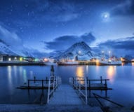 Рыбацкие лодки приближают к пристани на море и снежным горам на ноче Стоковые Фотографии RF Рыбацкие лодки приближают к пристани на море и снежным горам на ноче Стоковые Фотографии RF