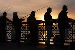Рыболовы в силуэте на восходе солнца, на мосте Galata, в Стамбуле, Турция стоковое фото rf Рыболовы в силуэте на восходе солнца, на мосте Galata, в Стамбуле, Турция стоковое фото rf