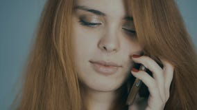 Рыжеволосая молодая женщина говоря по телефону и усмехаясь на предпосылке студии, эмоциях концепции, сообщении, технологии Рыжеволосая молодая женщина говоря по телефону и усмехаясь на предпосылке студии, эмоциях концепции, сообщении, технологии