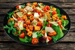 Сладкий картофель, моркови, томаты вишни и одичалый салат ракеты с сыром фета служили в черной плите Стоковые Изображения RF Сладкий картофель, моркови, томаты вишни и одичалый салат ракеты с сыром фета служили в черной плите Стоковые Изображения RF