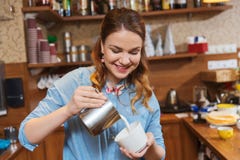 Сливк женщины Barista лить, который нужно придать форму чашки на кофейне стоковое фото Сливк женщины Barista лить, который нужно придать форму чашки на кофейне стоковое фото