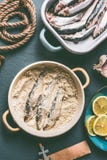 Сардины покрывают с мякишами хлеба на предпосылке кухонного стола с ингридиентами: лимон, чеснок и травы для вкусный варить мореп стоковое изображение rf Сардины покрывают с мякишами хлеба на предпосылке кухонного стола с ингридиентами: лимон, чеснок и травы для вкусный варить мореп стоковое изображение rf