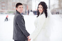 Свадьба зимы, жених и невеста держа руки смотря камеру, классический портрет пар в снежной улице Стоковое Изображение RF Свадьба зимы, жених и невеста держа руки смотря камеру, классический портрет пар в снежной улице Стоковое Изображение RF