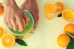 Свеже сжиманный апельсиновый сок руками ` s людей, в juicer бирюзы на белой предпосылке Стоковое Изображение RF Свеже сжиманный апельсиновый сок руками ` s людей, в juicer бирюзы на белой предпосылке Стоковое Изображение RF
