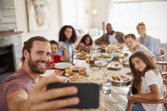 2 семьи принимая Selfie по мере того как они наслаждаются едой дома совместно стоковое фото 2 семьи принимая Selfie по мере того как они наслаждаются едой дома совместно стоковое фото