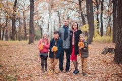 Семья, 3 дет в лесе, оставаясь в листьях осени стоковое фото Семья, 3 дет в лесе, оставаясь в листьях осени стоковое фото