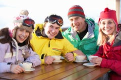 Семья наслаждаясь горячим питьем в кафе на лыжном курорте стоковые изображения rf Семья наслаждаясь горячим питьем в кафе на лыжном курорте стоковые изображения rf