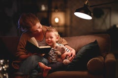 Семья перед идти положить мать в постель читает к ее книге сына ребенка около лампы в вечере стоковое изображение rf Семья перед идти положить мать в постель читает к ее книге сына ребенка около лампы в вечере стоковое изображение rf