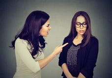 Сердитая женщина браня ее вспугнутые застенчивые сестру или друга стоковая фотография Сердитая женщина браня ее вспугнутые застенчивые сестру или друга стоковая фотография