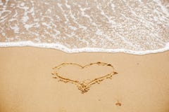 Сердце написанное на песчаном пляже с волной около моря человек влюбленности поцелуя принципиальной схемы к женщине H стоковые изображения rf Сердце написанное на песчаном пляже с волной около моря человек влюбленности поцелуя принципиальной схемы к женщине H стоковые изображения rf