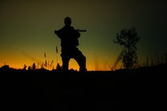 Силуэт воинских солдата или офицера с оружиями на ноче стоковое фото rf Силуэт воинских солдата или офицера с оружиями на ноче стоковое фото rf