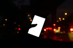 Силуэт в ноче автомобиля с прифронтовым взглядом современного умного телефона и пустого белого экрана пустых для космоса экземпля стоковая фотография Силуэт в ноче автомобиля с прифронтовым взглядом современного умного телефона и пустого белого экрана пустых для космоса экземпля стоковая фотография
