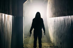 Силуэт маниака человека или убийцы или душегуба ужаса с ножом в руке в темном страшном и пугающем коридоре стоковое фото rf Силуэт маниака человека или убийцы или душегуба ужаса с ножом в руке в темном страшном и пугающем коридоре стоковое фото rf
