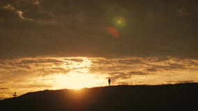 Силуэт молодой девушки hiker с рюкзаком на верхних горах на заходе солнца сток-видео Силуэт молодой девушки hiker с рюкзаком на верхних горах на заходе солнца сток-видео