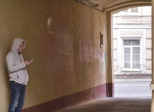 Силуэт человека в клобуке с положением телефона в своде двора стоковая фотография Силуэт человека в клобуке с положением телефона в своде двора стоковая фотография