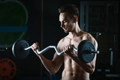 Сильный мышечный человек разрабатывая в спортзале делая тренировки с штангой на бицепсе стоковая фотография rf Сильный мышечный человек разрабатывая в спортзале делая тренировки с штангой на бицепсе стоковая фотография rf