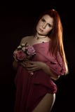 Симпатичная женщина redhead в прозрачной накидке с букетом на черной предпосылке стоковая фотография Симпатичная женщина redhead в прозрачной накидке с букетом на черной предпосылке стоковая фотография