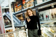 Симпатичная молодая женщина смотря на мобильном телефоне в торговом центре стоковые фото Симпатичная молодая женщина смотря на мобильном телефоне в торговом центре стоковые фото
