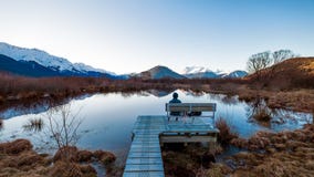 Сиротливый человек сидя на стенде в Glenorchy, Новой Зеландии стоковые изображения Сиротливый человек сидя на стенде в Glenorchy, Новой Зеландии стоковые изображения
