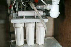 Система очистки воды обратного осмоза дома Установка фильтров очистки воды под кухонной раковиной в кухонном шкафе стоковые фотографии rf Система очистки воды обратного осмоза дома Установка фильтров очистки воды под кухонной раковиной в кухонном шкафе стоковые фотографии rf