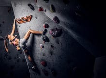 Скалолазание sportswear молодой женщины нося практикуя на стене внутри помещения стоковое фото Скалолазание sportswear молодой женщины нося практикуя на стене внутри помещения стоковое фото