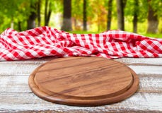Скатерть стола пиццы checkered на деревянном столе на запачканной предпосылке леса стоковые изображения rf Скатерть стола пиццы checkered на деревянном столе на запачканной предпосылке леса стоковые изображения rf