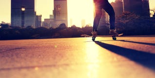 Скейтбордист женщины skateboarding на городе восхода солнца стоковая фотография Скейтбордист женщины skateboarding на городе восхода солнца стоковая фотография