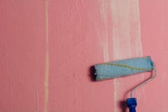 Склонность ролика краски против розовой стены, с белым brushstroke стоковое изображение Склонность ролика краски против розовой стены, с белым brushstroke стоковое изображение